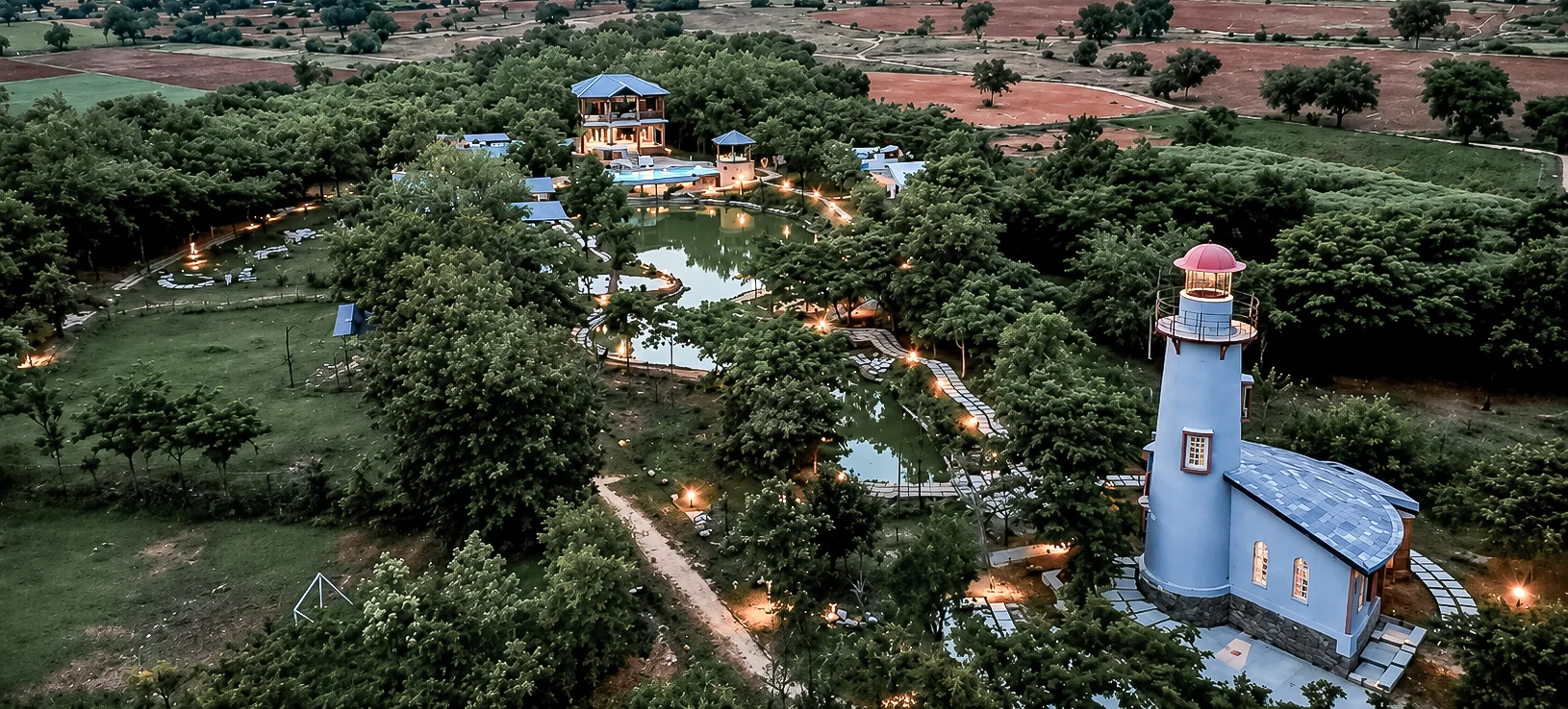 Arbor Road Estate illuminated at dusk amid gardens, a luxury resort near Hyderabad.