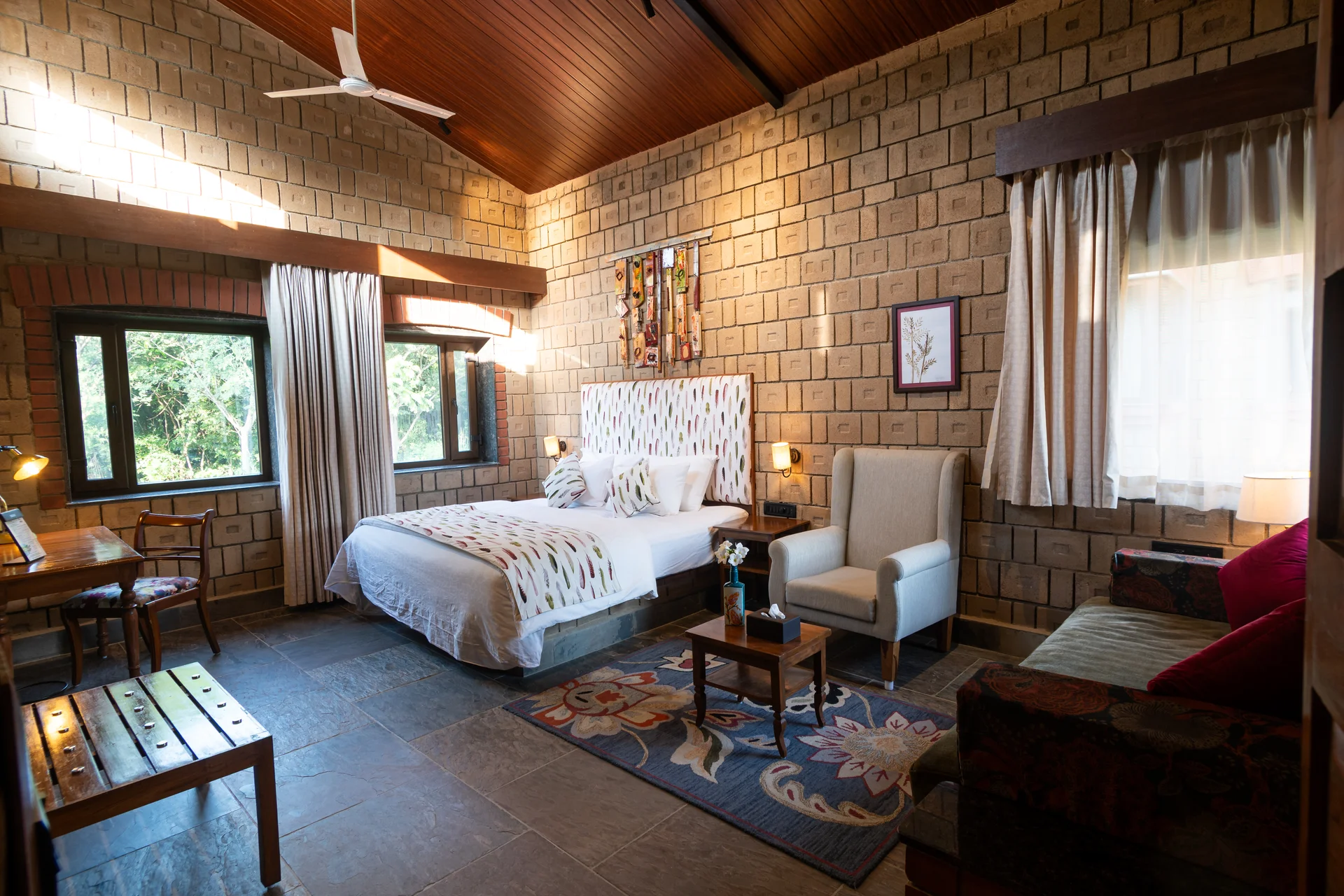 Earth-built guest room with a bed, seating and garden views at Arbor Road Estate near Hyderabad.